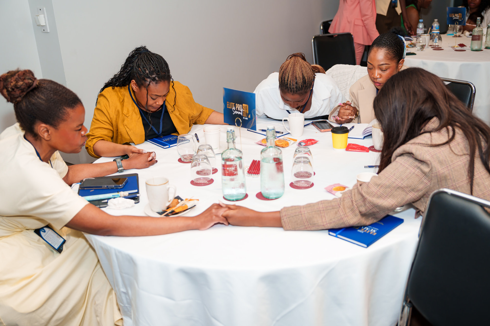 Christian professionals holding hands in prayer around a table at a Christian in Corporate gathering